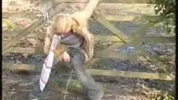 Woman pissing in a wooden fence