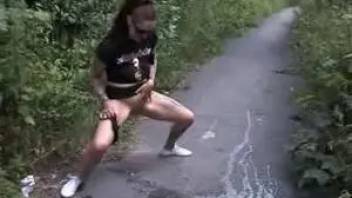 Crazy girl friend pissing on the path between the bushes