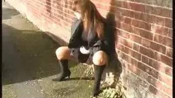 Woman in boots pissing in the street